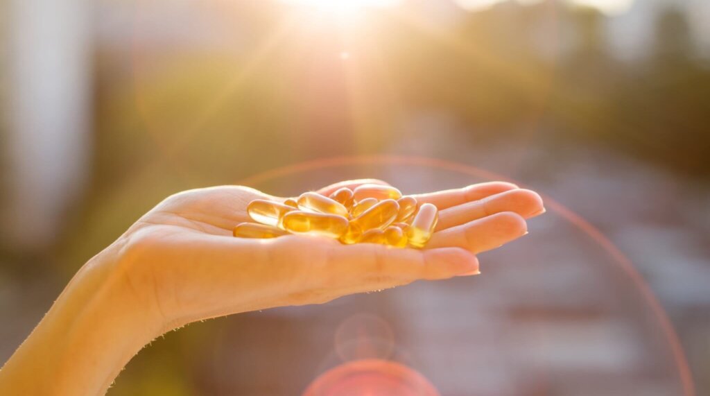 Hand holding vitamin D capsules under sunlight