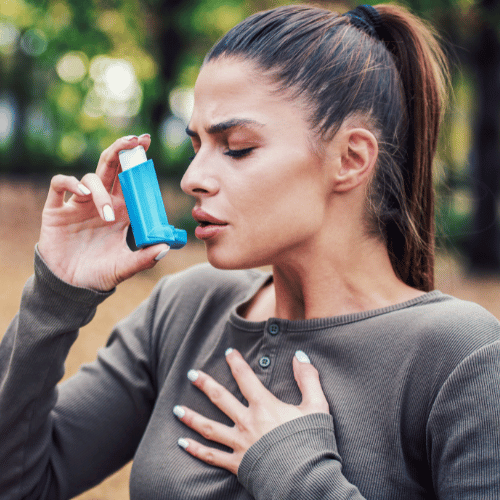 Young woman treating asthma with inhaler
