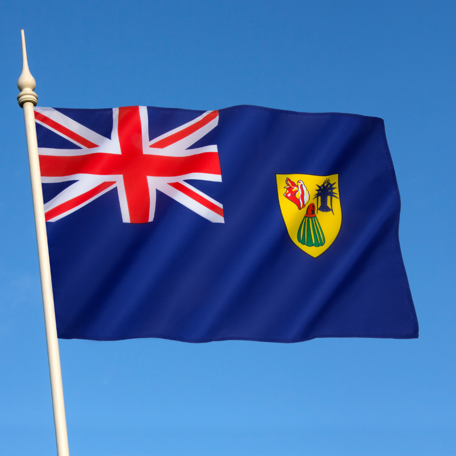 Turks And Caicos flag waving against a clear blue sky.